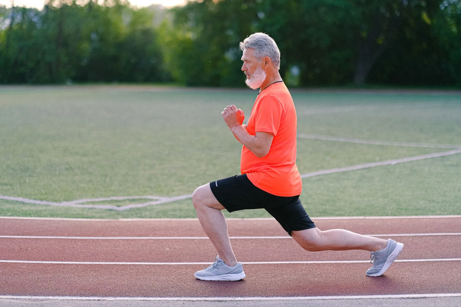 Coureur en train d'exécuter des fentes sur une piste d'athlétisme