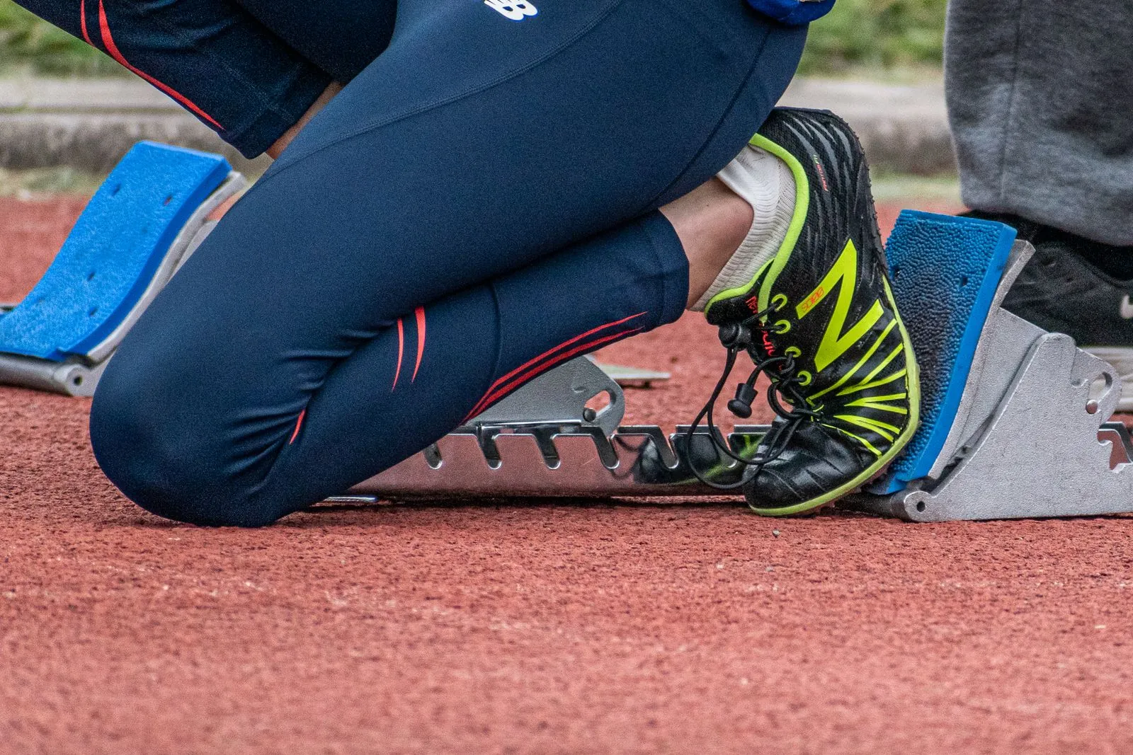 Jambes d'un coureur positionné dans des starting-blocks sur la piste