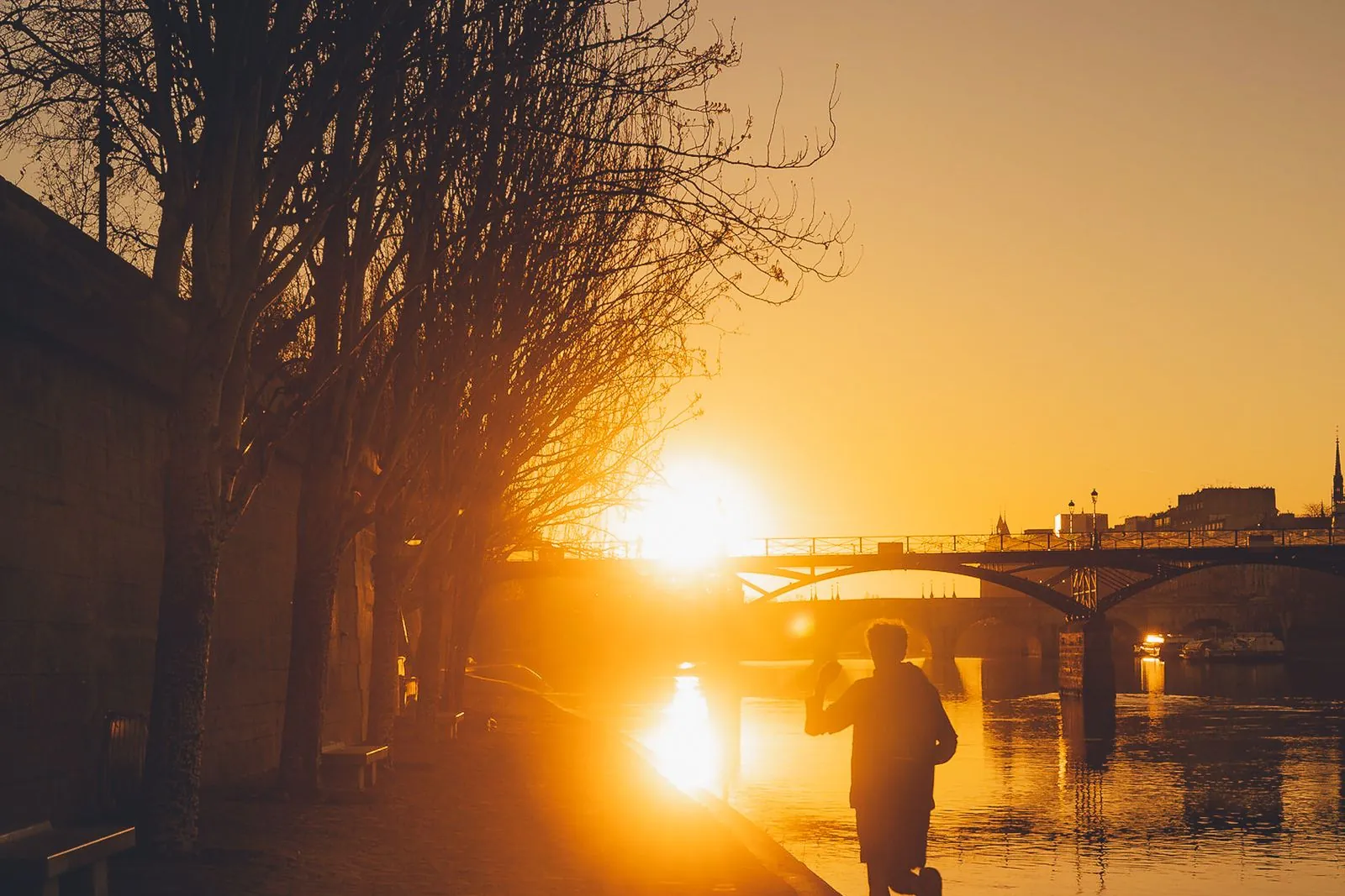 Silhouette d'un coureur au coucher du soleil au bord de la Seine