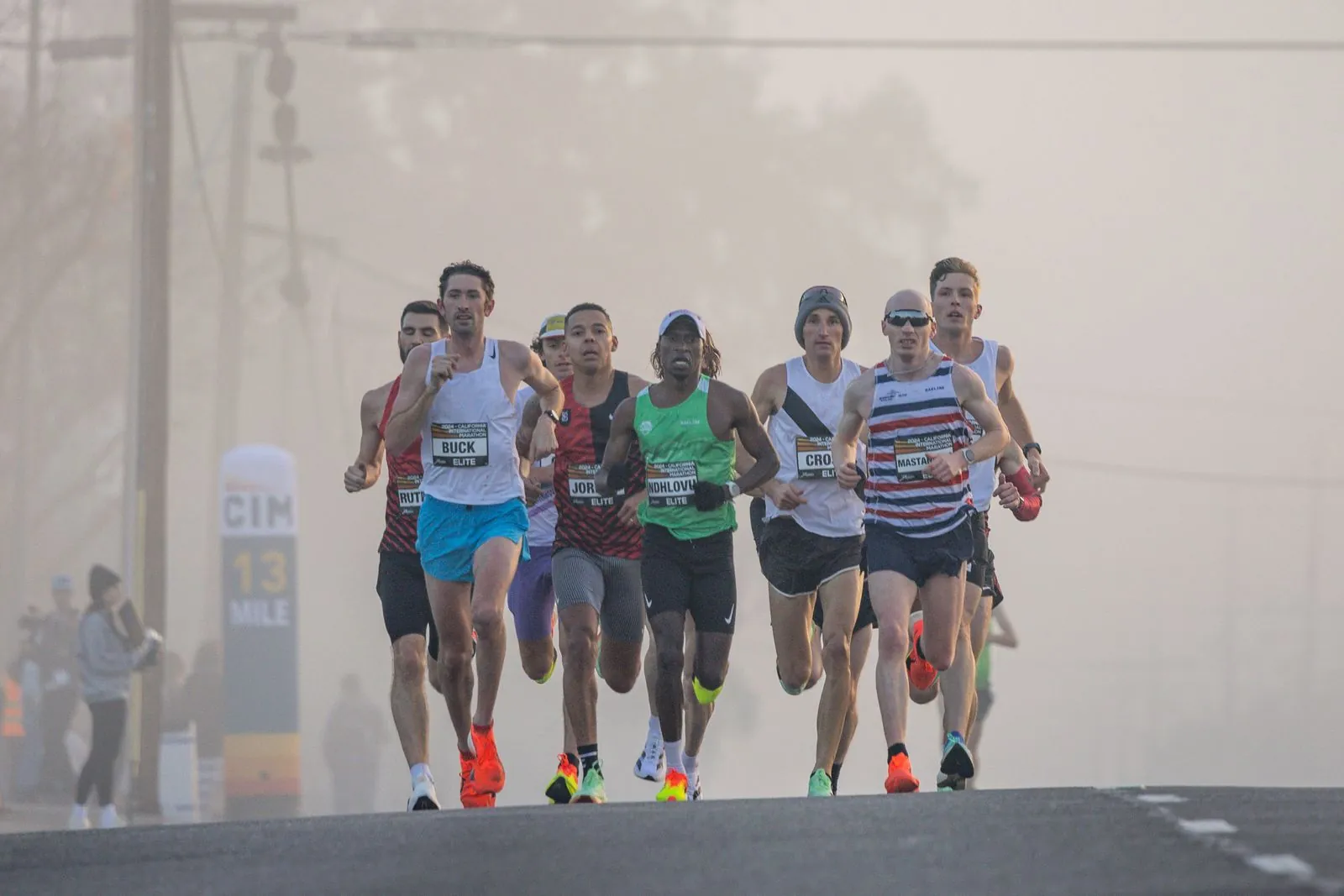 Peloton de marathoniens courant dans la brume urbaine au petit matin